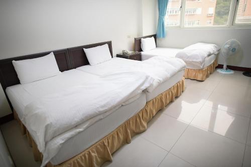 two beds in a room with white walls at Clear Water Bay Homestay in Nangan