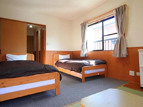 a bedroom with two beds and a window at Karuizawamura Hotel in Karuizawa