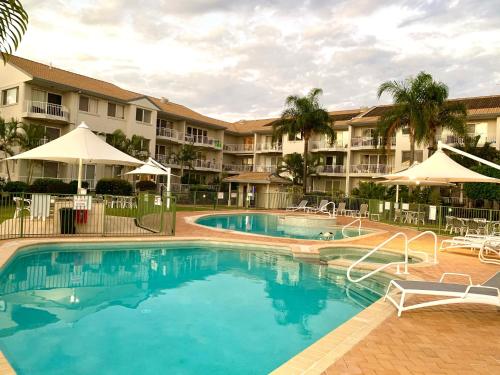 a hotel room with a pool and lawn chairs at Pelican Cove Apartments in Gold Coast