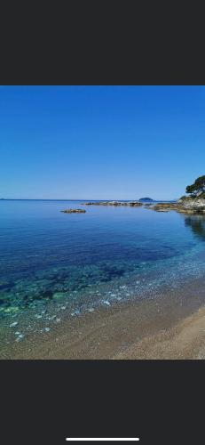 a beach with blue water and rocks in the distance at Il Delfino in Tellaro