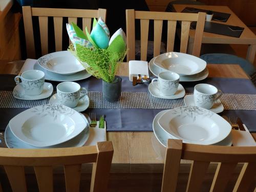 a table with plates and cups and a plant on it at Apartamenty przy Jeziorze Żywieckim z widokiem na Skrzyczne in Żywiec
