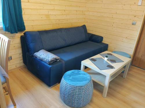 a living room with a blue couch and a table at Apartamenty przy Jeziorze Żywieckim z widokiem na Skrzyczne in Żywiec