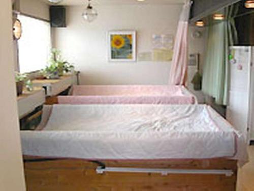 a hospital room with three beds with pink sheets at Ryokan Kume Himawari Sou in Sakaide
