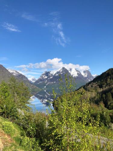 a view of a mountain lake with snow covered mountains at Tunold Gård - Freden in Stryn