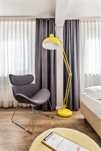 a yellow lamp and a chair in a bedroom at Best Western Hotel Das Donners in Cuxhaven