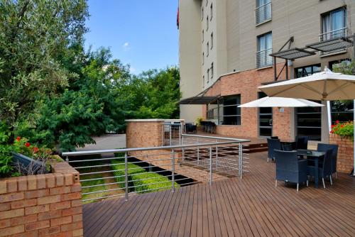 a patio with tables and an umbrella next to a building at City Lodge Hotel Fourways in Johannesburg