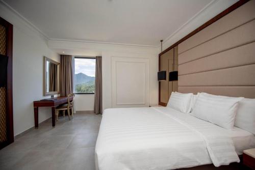een slaapkamer met een groot wit bed en een bureau bij Mahkota Hotel Singkawang in Singkawang