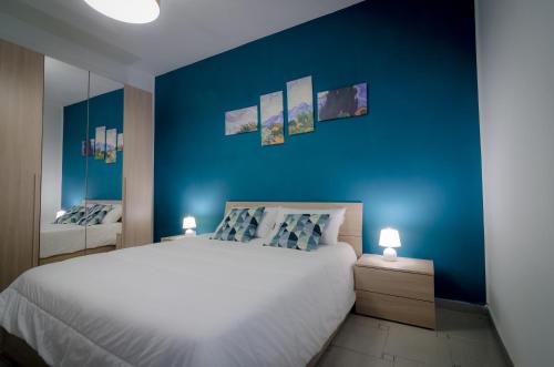 una camera da letto con un grande letto bianco e pareti blu di Nest Home Sorrento a Sorrento