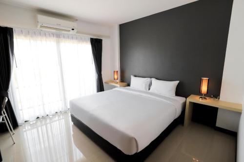Un dormitorio con una gran cama blanca y una ventana en The Rest Hotel - ประจวบ en Prachuap Khiri Khan