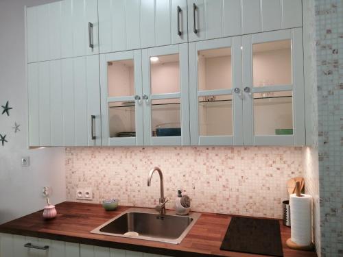 a kitchen with white cabinets and a sink at Enklawa Mielno przy plaży in Mielno