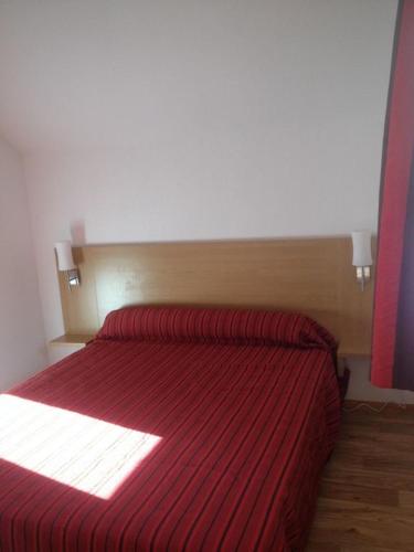 - une chambre avec un lit rouge et une couverture rayée rouge dans l'établissement CHALET DE BOIS MEAN, aux Orres