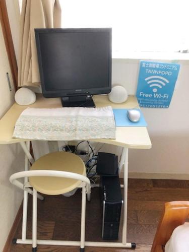 a desk with a computer monitor and a chair at Fuji Gotemba Condominium Tannpopo in Gotemba