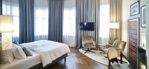 a hotel room with a bed, chair, desk and television at Steigenberger Hotel Herrenhof in Vienna