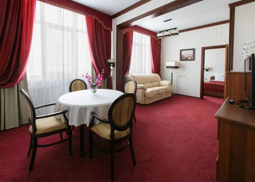 una habitación con mesa y sillas y un dormitorio en Tatarstan Business-Hotel en Naberezhnye Chelny