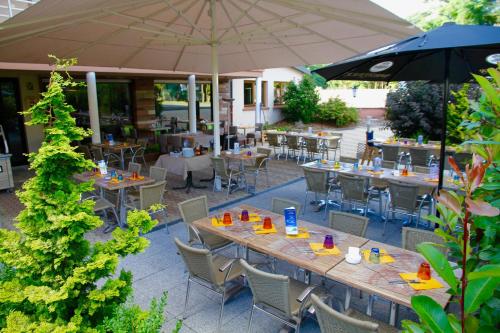 an outdoor patio with tables and chairs and an umbrella at Hôtel Le Verger De Bischwiller in Bischwiller