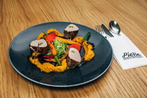a plate of food with meat and vegetables on a table at Pierre Hotel in Pardubice