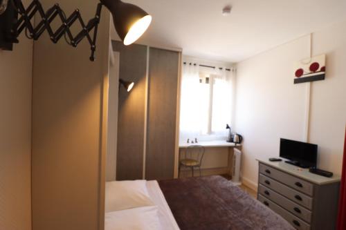 a bedroom with a bed and a desk and a television at AUBERGE LE GABACHOU in Montpezat-de-Quercy