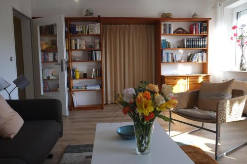 uma sala de estar com um vaso de flores sobre uma mesa em Ferienwohnung Liene em Bad Zwischenahn