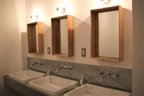 a bathroom with three sinks and two mirrors at Iwashi Building Hostel in Akune