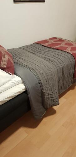 a bed with a gray blanket on top of it at Lentävä Kalakukko -Veturi B&B in Kuopio