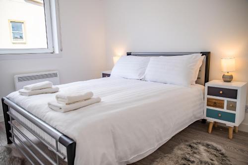 ein Schlafzimmer mit einem großen weißen Bett mit Handtüchern darauf in der Unterkunft Millburn Apartment in Inverness
