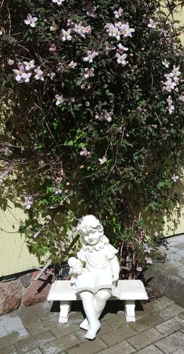 a statue of a little girl sitting on a bench at Vila Florena Garden in Palanga