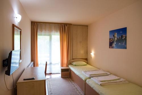 a room with two beds and a desk and a television at Tourist center Momina Krepost in Veliko Tŭrnovo