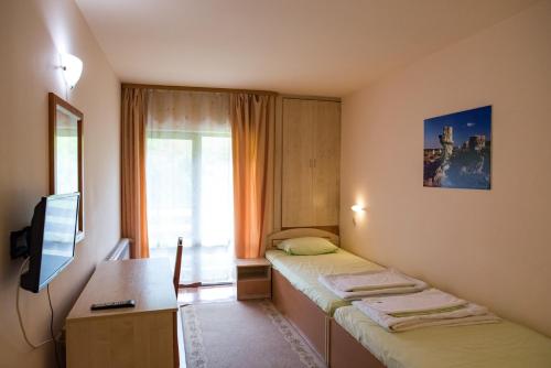 ヴェリコ・タルノヴォにあるTourist center Momina Krepostのベッド2台、デスク、テレビが備わる客室です。
