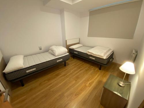 two beds in a small room with wooden floors at P&C Ribasol in Arinsal
