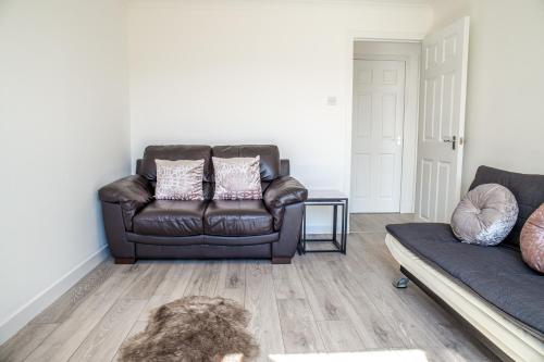 un soggiorno con poltrona in pelle e divano di Millburn Apartment a Inverness