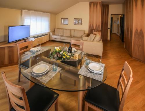 a dining room and living room with a glass table and chairs at Appartamenti Pirovano Bormio in Bormio