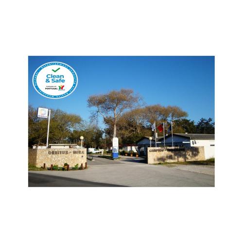 a sign for a parking lot at a park with trees at Parque de Campismo Orbitur Mira in Praia de Mira