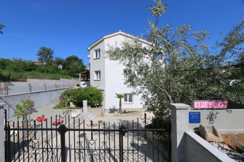 a white house with a gate in front of it at Apartments Mirjana in Šilo