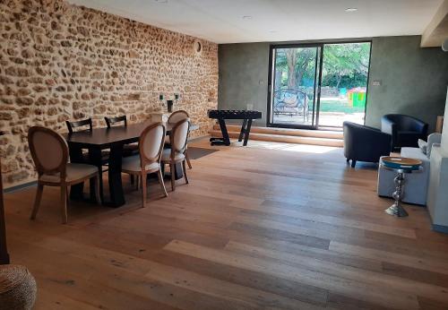 d'une salle à manger avec une table, des chaises et un mur en briques. dans l'établissement Maison d'hôtes 1800, à Sainte-Cécile-les-Vignes