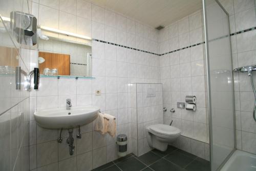 a bathroom with a sink and a toilet and a shower at Landgasthof Auerschmiede in Irschenberg