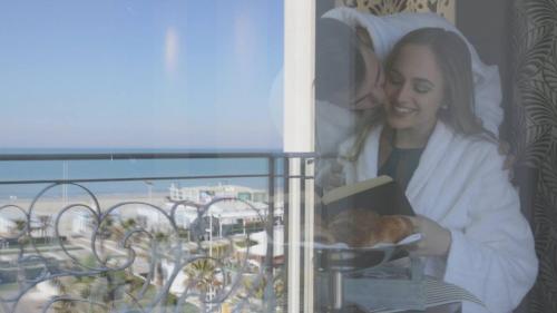 a woman sitting on a balcony reading a book at Hotel Corallo in Riccione
