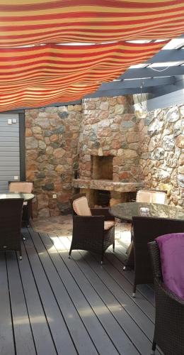 a patio with tables and chairs and a stone wall at Vila Florena Garden in Palanga