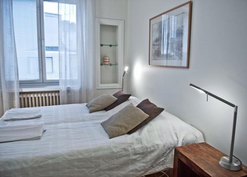 1 dormitorio con 1 cama con sábanas y almohadas blancas en Helsinki Apartments, en Helsinki