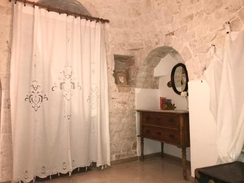 a room with a white curtain and a dresser at Aria di Casa Country Resort in Alberobello