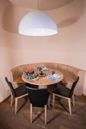 a dining room table with chairs and a large light fixture at Appartamenti Pirovano Bormio in Bormio
