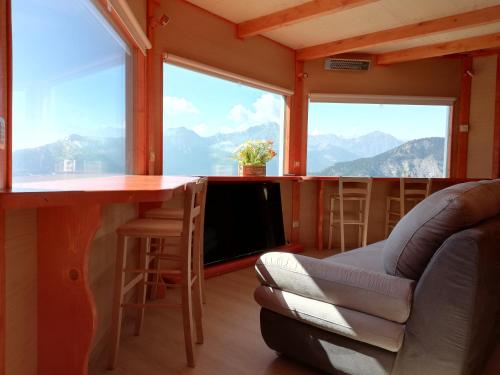 a living room with a table and chairs and windows at DalaiLama Village in Antey-Saint-André