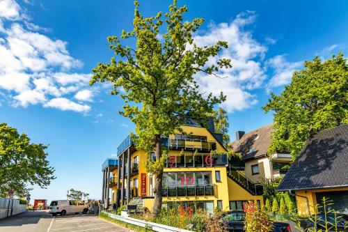 a yellow building with a tree in front of it at Seaside-Strandhotel in Timmendorfer Strand