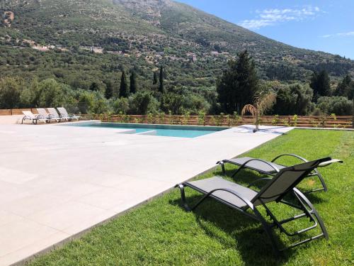 a chair sitting on the grass next to a swimming pool at Diosas Luxury Villas in Pilaroú