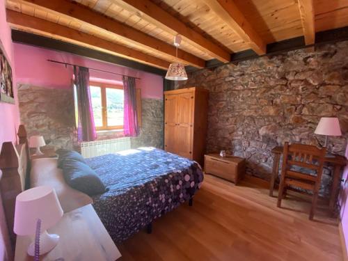 a bedroom with a bed and a stone wall at Alojamientos Casa San Apartamentos in Besande