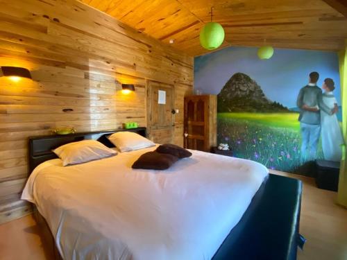 a bedroom with a large bed with a painting on the wall at Maison d´hôtes La Dromandise in Saint-Arcons-de-Barges