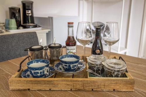 Bed and Breakfast: 'Bij ons Achter' في Helvoirt: صينية خشبية مع زجاجات النبيذ والاكواب على طاولة