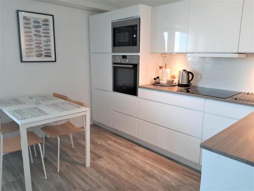 a kitchen with white cabinets and a table with chairs at Seaside Downtown Apartment in Helsinki