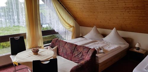 a bedroom with a bed and a table and a window at Pension Gerlach in Seiffen