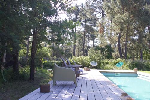 une terrasse avec des chaises à côté d'une piscine dans l'établissement Chambres d'Hôtes 1001 NUITS Montalivet, à Vendays-Montalivet