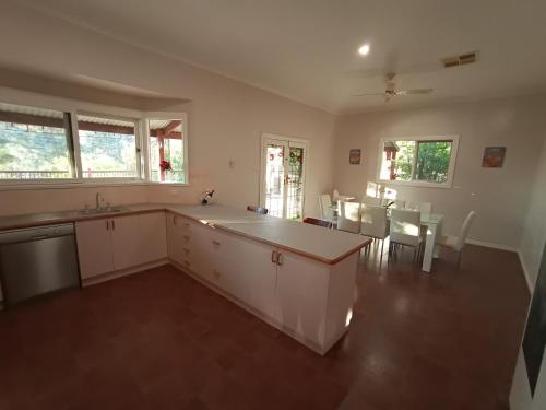a kitchen with white cabinets and a table and chairs at Treetops Escape Albury in Albury